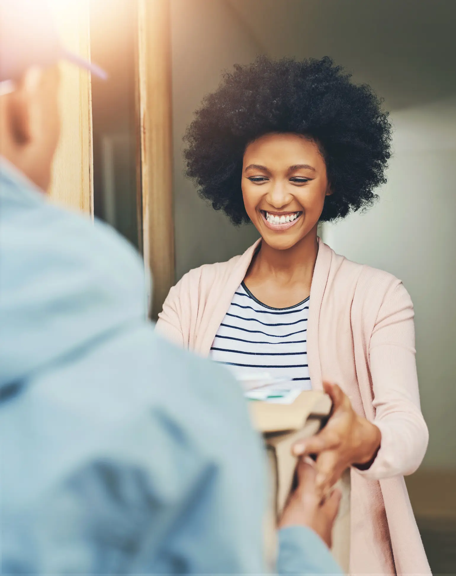 A woman smiling while handing a cup to someone.