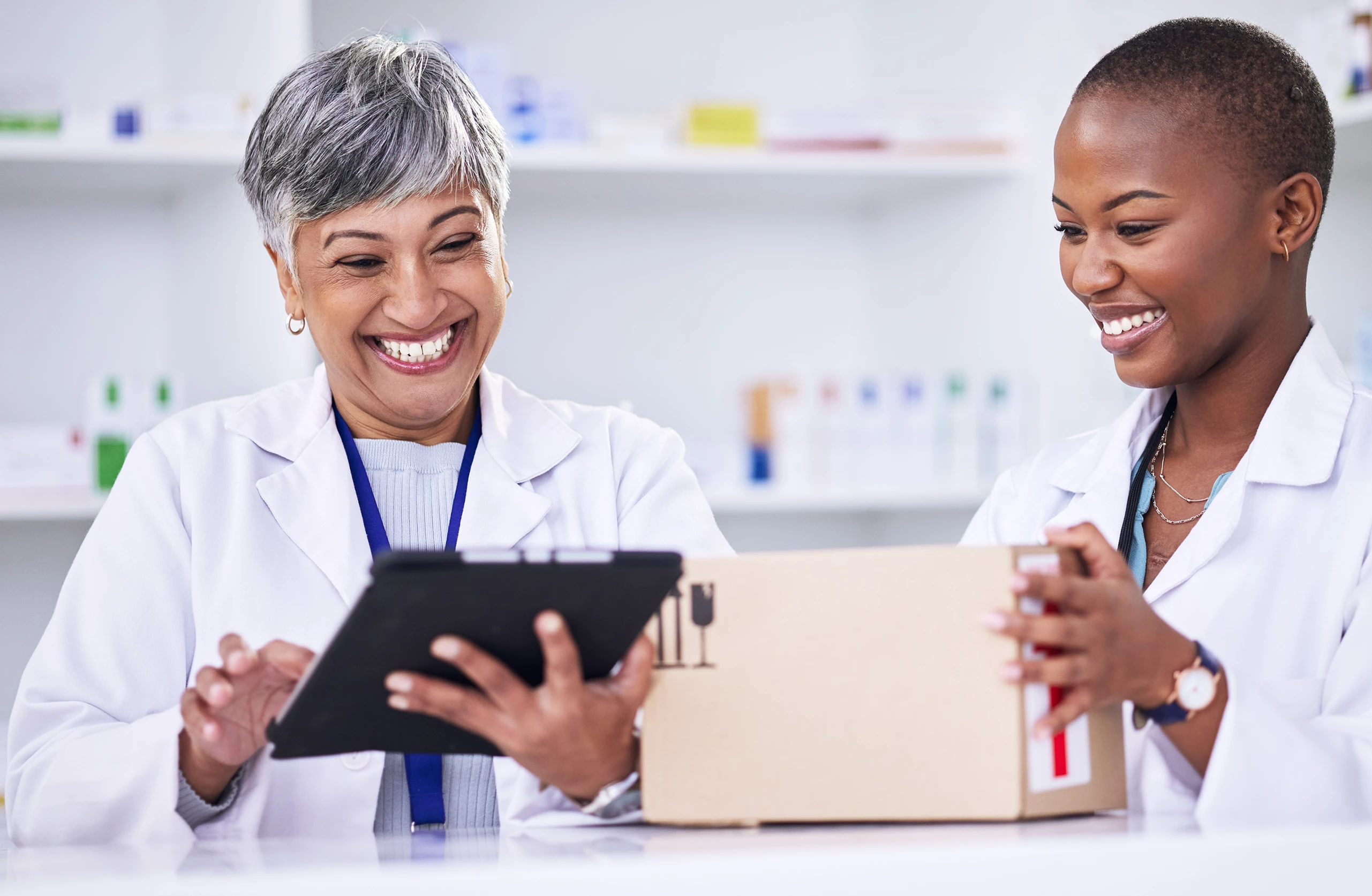 Two healthcare professionals reviewing information on a tablet with a package.